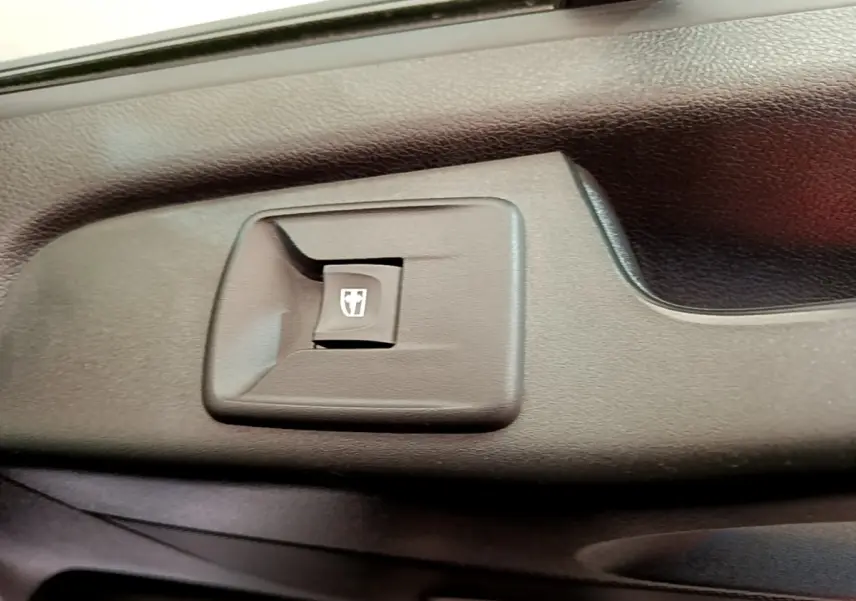 Gros plan sur le bouton de commande de la vitre électrique côté conducteur du Renault Trafic Fourgon blanc.