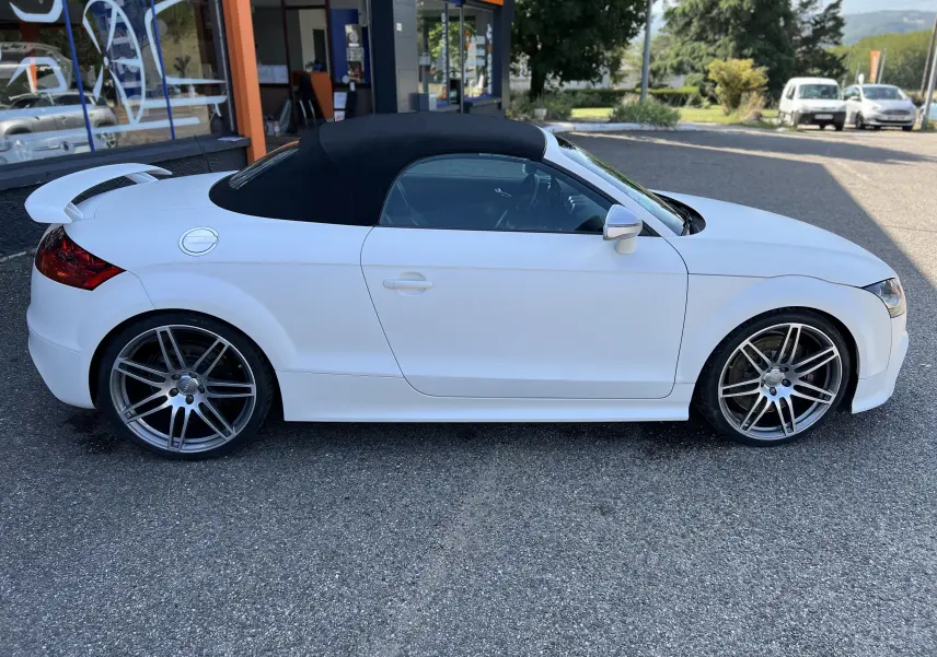 Audi TT RS Roadster blanc vue de profil côté gauche avec capote noire et jantes sport grises.