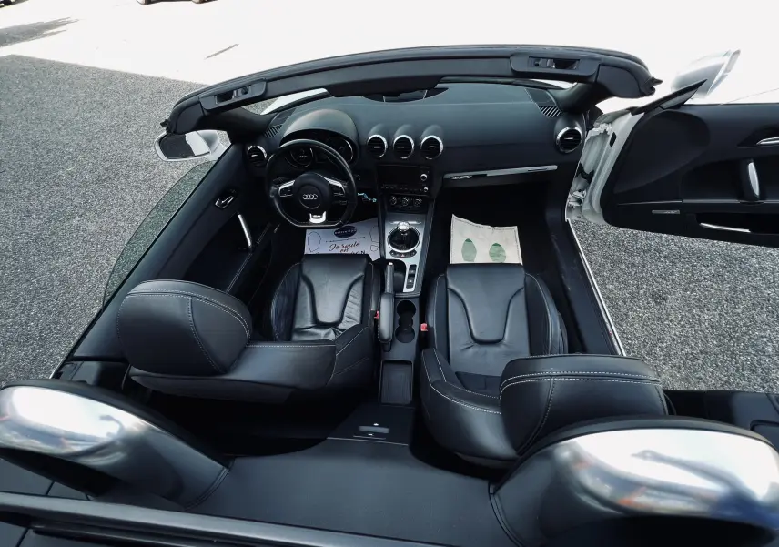 Vue plongeante de l'intérieur noir cuir de l'Audi TT RS Roadster cabriolet blanc avec volant multifonction et boîte manuelle.