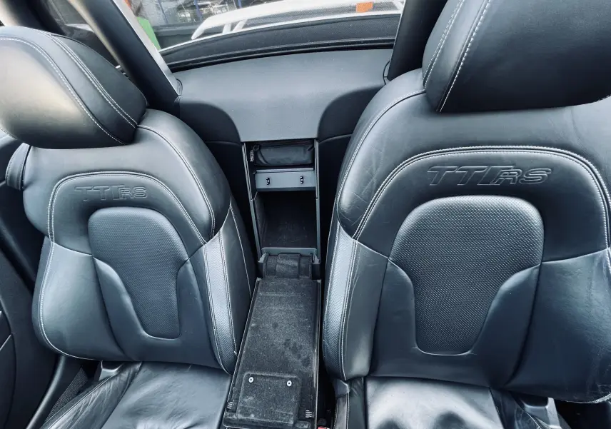 Gros plan sur les sièges baquet noirs en cuir embossés TT RS de l'Audi TT RS Roadster blanc, vue intérieure avant.