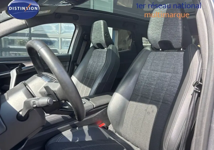 Intérieur du Renault Austral 2024 montrant les sièges avant en tissu gris et cuir noir sous lumière naturelle.