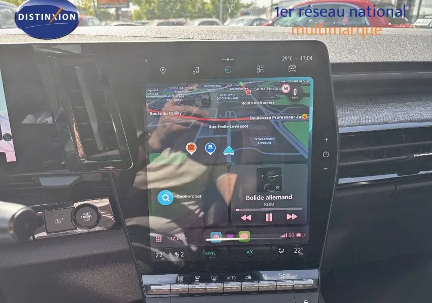 Vue rapprochée de l'écran tactile central du tableau de bord du Renault Austral gris schiste, affichant la navigation et la musique.
