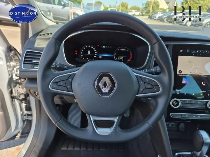 Vue centrée sur le volant multifonction d'une Renault Mégane Break gris titanium avec tableau de bord numérique et écran tactile.