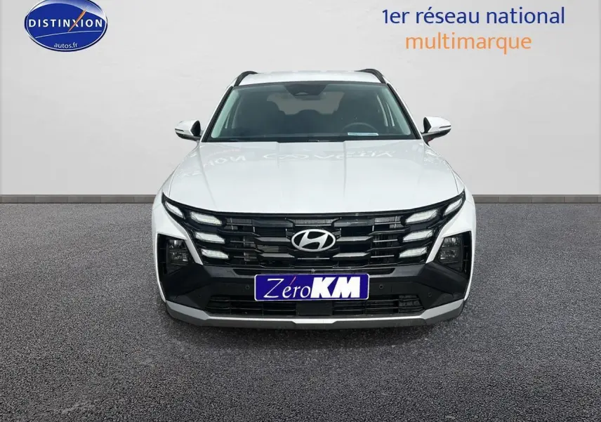 Vue avant d'un Hyundai Tucson blanc Sérénité 2025 avec calandre noire et logo Hyundai visible.