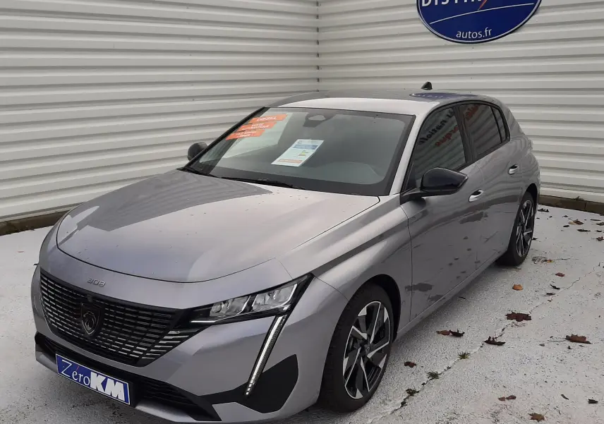 Peugeot 308 gris Artense vue 3/4 avant droit, avec calandre distinctive et jantes alliage bicolores.