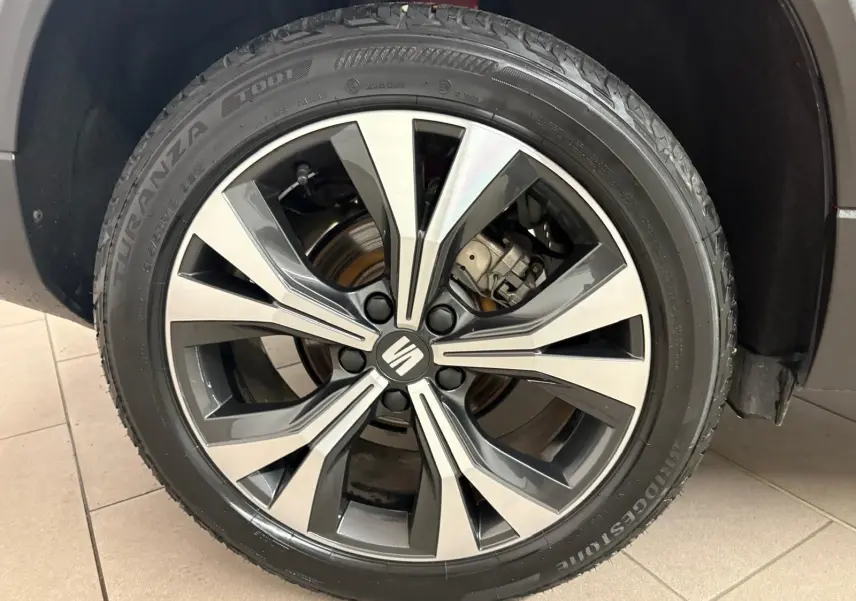 Gros plan sur la roue avant droite du SEAT Ateca 2024 Rouge Velvet avec jante alliage bicolore et logo central.