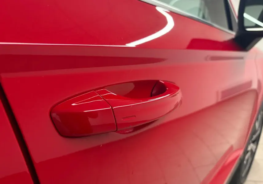 Poignée de porte côté droit rouge métallisée du SEAT Ateca 2024 vue en gros plan avec reflet lumineux.