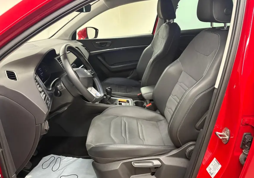 Vue intérieure côté conducteur du SEAT Ateca Rouge Velvet 2024, montrant les sièges en cuir noir et la boîte manuelle.