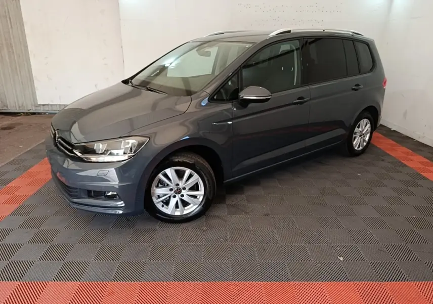 Volkswagen Touran gris clair vu en 3/4 avant droit, avec jantes alliage et vitres teintées.