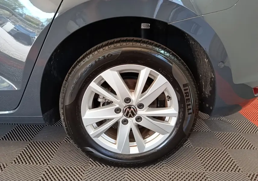 Gros plan sur la roue arrière droite d’un Volkswagen Touran gris clair, jante alliage et pneu Pirelli visible.