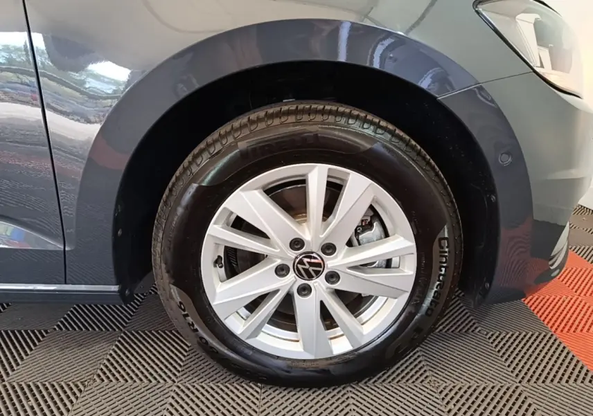 Gros plan sur la roue avant droite gris clair du Volkswagen Touran 2024 avec jante alliage et logo VW central.