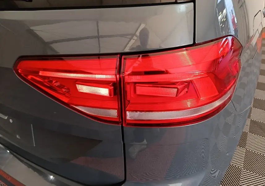 Gros plan sur le feu arrière droit rouge d’un Volkswagen Touran gris clair 2024, avec carrosserie brillante.