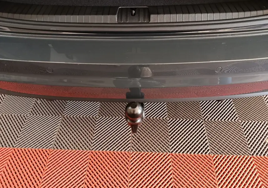 Vue rapprochée de l'attelage de remorque sous le pare-chocs arrière gris clair du Volkswagen Touran 2024.