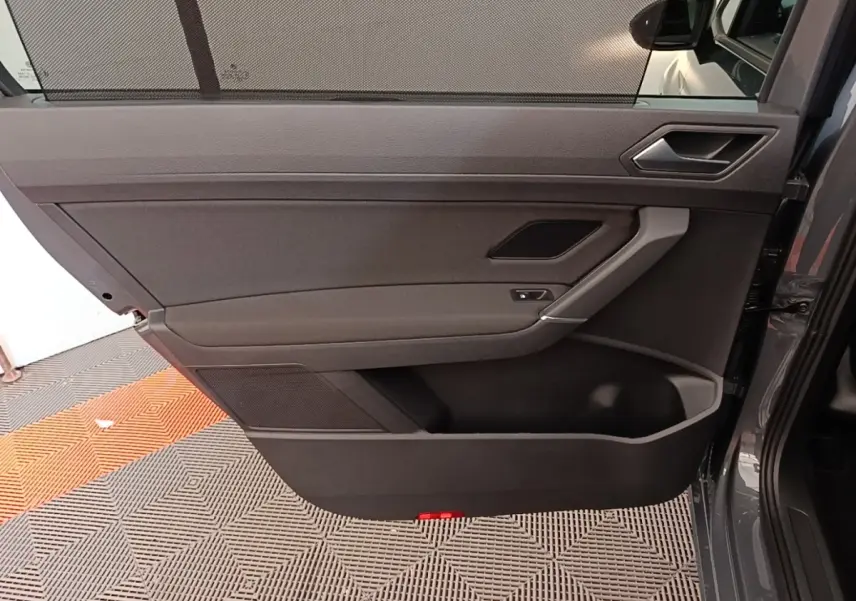 Vue intérieure de la porte arrière droite du Volkswagen Touran gris clair, avec poignée et haut-parleur intégrés.