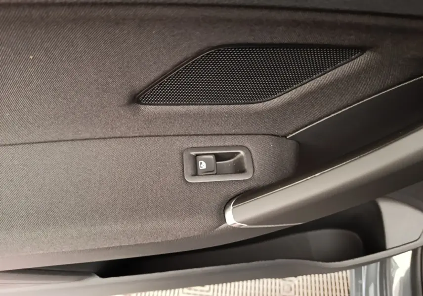 Gros plan sur la poignée intérieure et le bouton de verrouillage de la porte côté conducteur d’un Volkswagen Touran gris clair.
