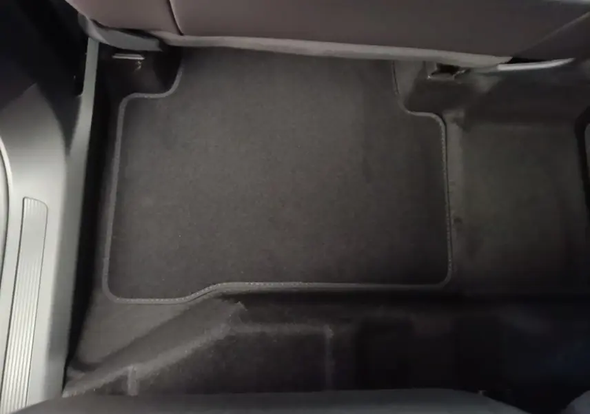 Vue rapprochée du tapis de sol noir côté passager avant du Volkswagen Touran 2024 gris clair.