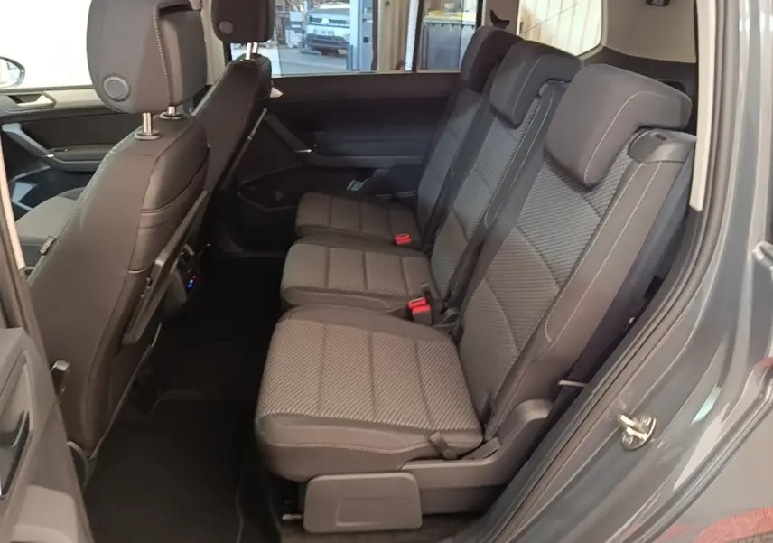 Vue latérale intérieure du siège arrière droit gris foncé du Volkswagen Touran 2024, montrant trois places avec appuie-têtes.