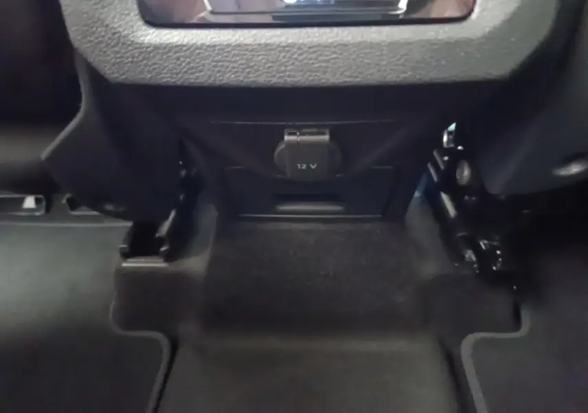Prise 12V sous la console centrale arrière du Volkswagen Touran gris clair, vue rapprochée du plancher.