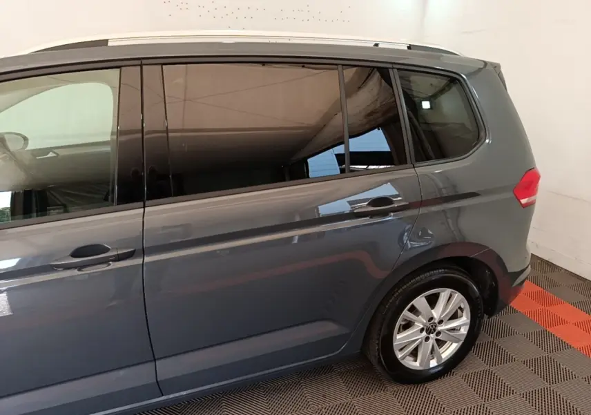 Vue latérale droite d'un Volkswagen Touran gris clair 2024 avec vitres teintées et jantes alliage.