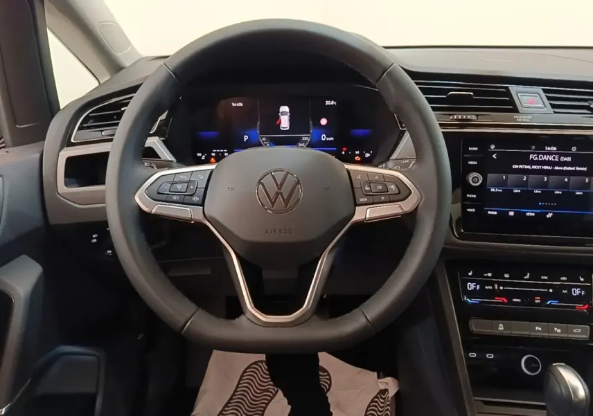 Vue intérieure centrée sur le volant cuir noir et le combiné numérique du Volkswagen Touran 2024, tableau de bord moderne.
