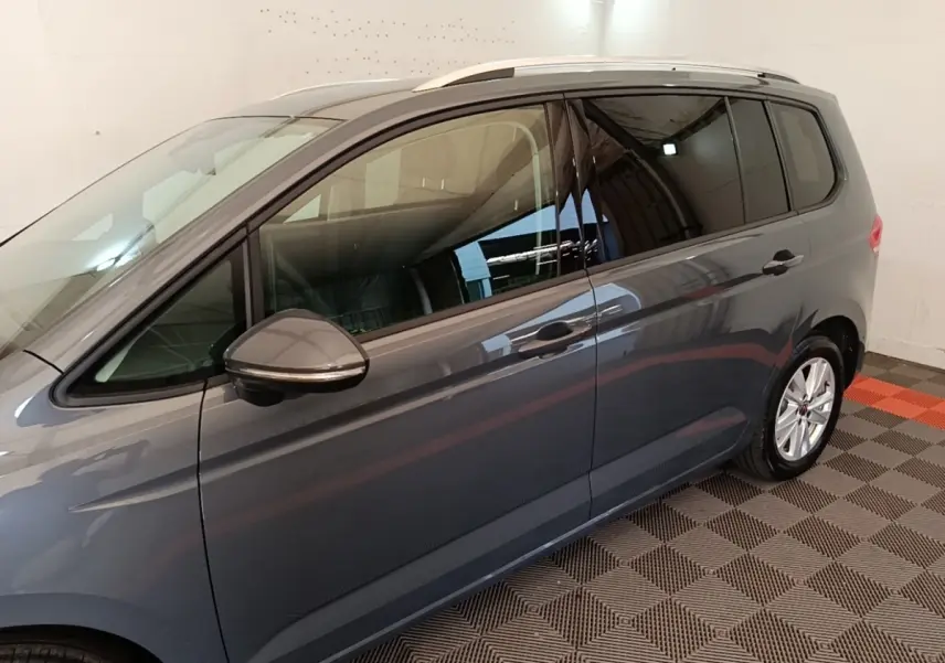 Vue latérale droite d'un Volkswagen Touran gris clair 2024, avec rétroviseur et vitres teintées visibles.