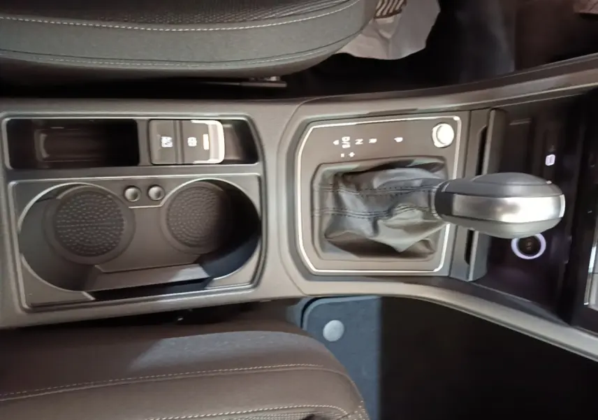 Vue rapprochée de la console centrale du Volkswagen Touran 2024 avec levier de vitesse automatique et porte-gobelets noirs.