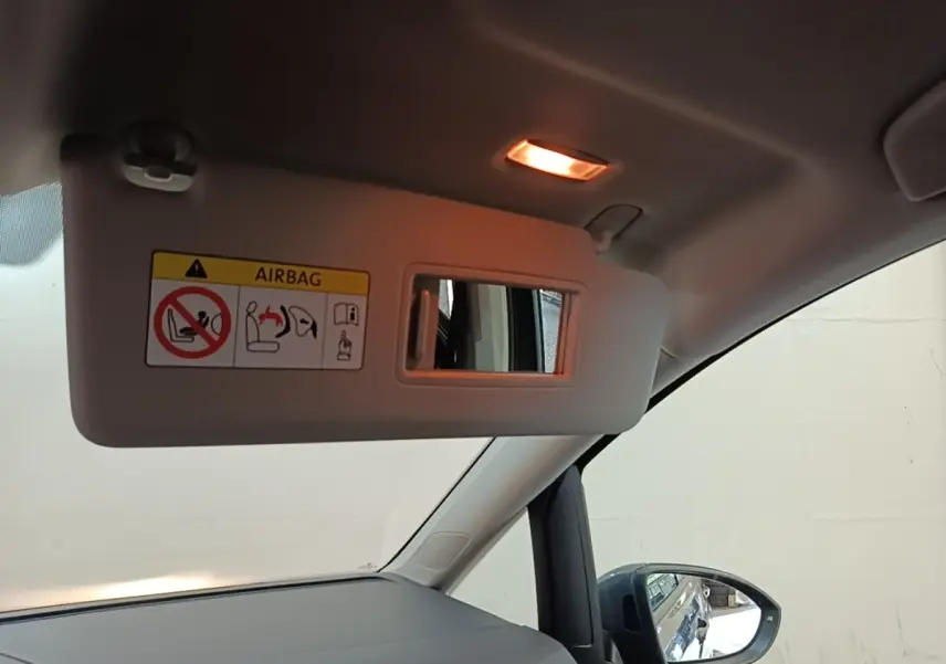 Intérieur du Volkswagen Touran 2024, vue côté passager avec pare-soleil ouvert et rétroviseur extérieur gris clair visible.