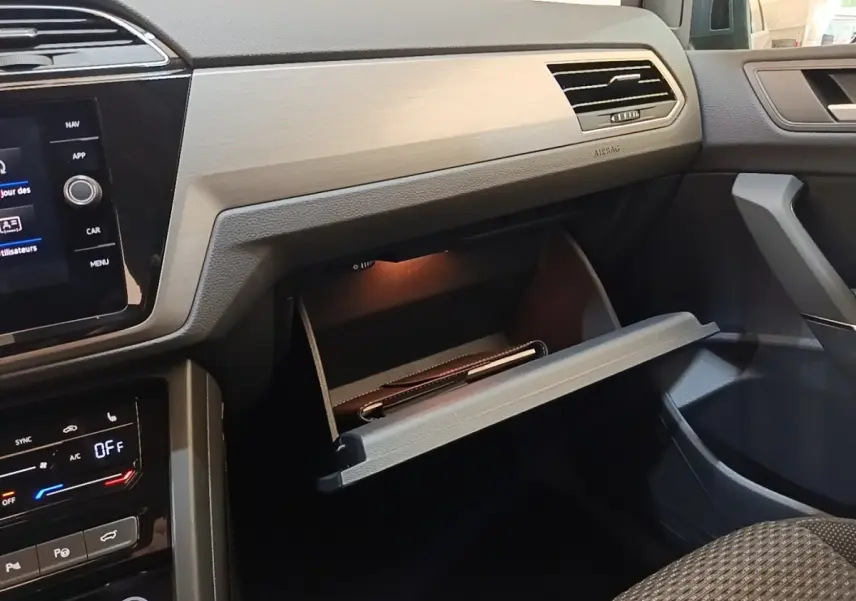 Intérieur Volkswagen Touran 2024 gris clair, vue côté passager avec boîte à gants ouverte et tableau de bord moderne.
