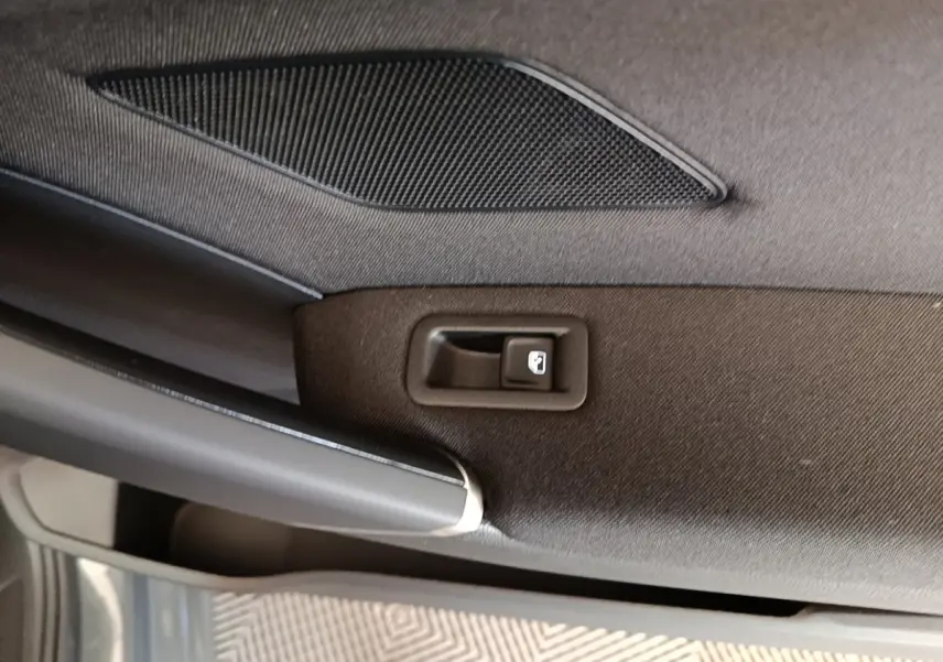 Détail intérieur de la porte arrière droite du Volkswagen Touran gris clair, avec bouton de verrouillage et haut-parleur intégré.