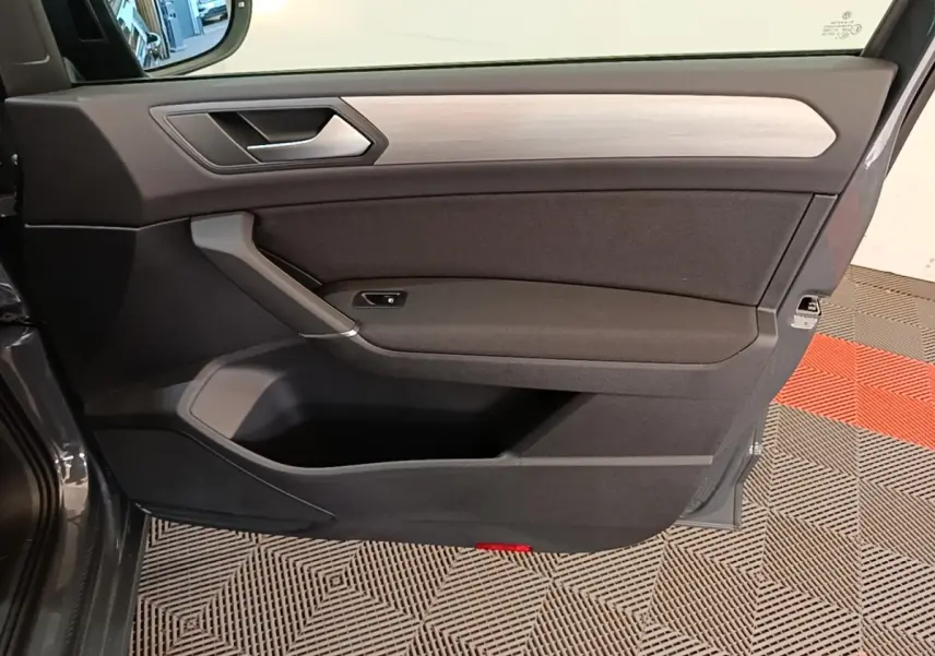 Vue intérieure de la porte avant gauche du Volkswagen Touran gris clair 2024 avec insert décoratif bois clair.