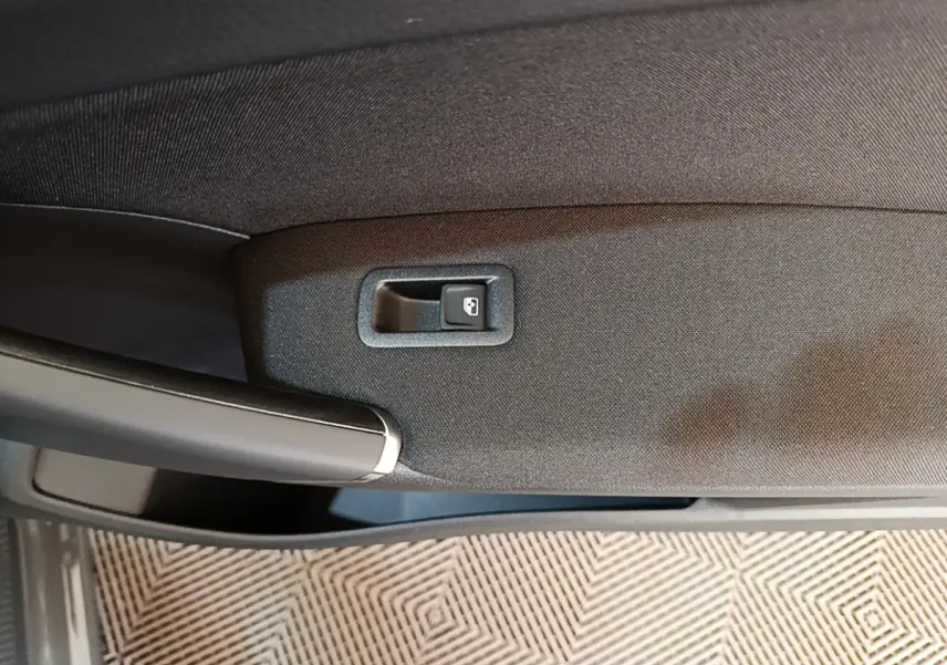 Détail de la poignée intérieure et bouton de verrouillage de porte du Volkswagen Touran gris clair 2024.
