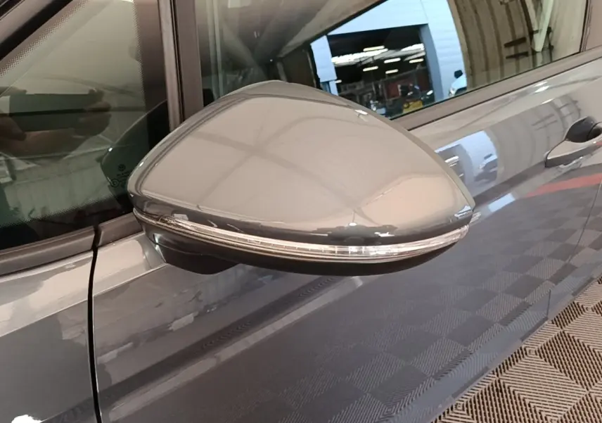 Rétroviseur droit gris clair du Volkswagen Touran 2024 avec clignotant intégré, vue rapprochée côté passager.
