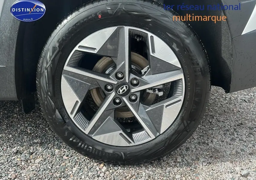 Gros plan sur la roue avant gauche du Hyundai Tucson blanc Sérénité avec jante alliage 18 pouces design moderne.