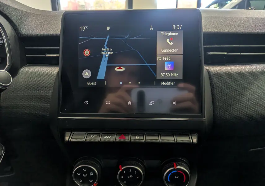 Vue rapprochée de l'écran tactile central et des commandes de climatisation d'une Renault Clio V blanche Glacier de 2020.