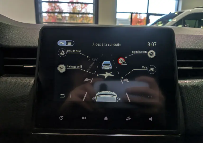Écran tactile intérieur de la Renault Clio V blanc glacier affichant les aides à la conduite et la distance de suivi.