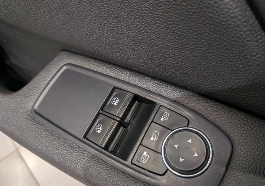 Gros plan sur les commandes de lève-vitres et rétroviseurs côté gauche intérieur d'une Renault Clio V blanc glacier.