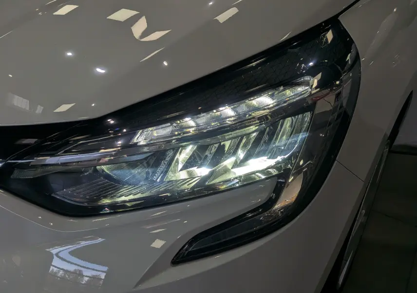 Gros plan sur le phare avant droit blanc glacier d'une Renault Clio V TCe 100 CH BUSINESS 2020, éclairage LED visible.