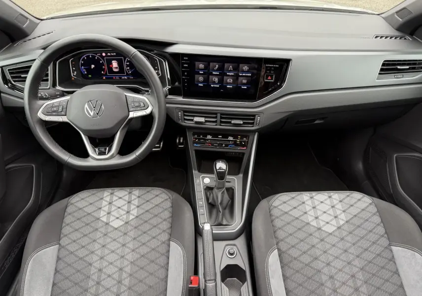 Intérieur Volkswagen Taigo 2024, vue du poste de conduite avec volant multifonction et écran tactile central.
