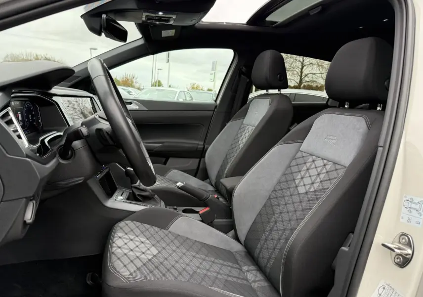 Vue intérieure côté gauche du Volkswagen Taigo 2024 avec sièges avant R-Line en tissu gris et toit ouvrant panoramique.