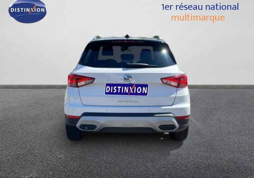 Vue arrière d'une SEAT Arona blanche avec toit noir, affichant ses feux arrière et son logo central.