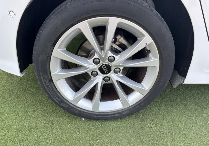 Gros plan sur la jante alliage 5 branches parallèles de l'Audi A3 Sportback blanc Arkona côté avant droit.