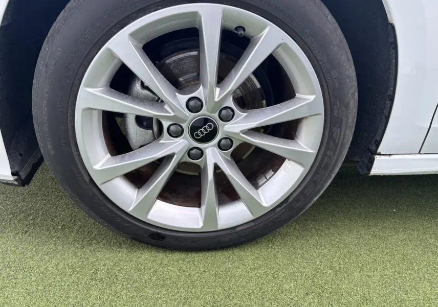 Gros plan sur la jante alliage 5 branches parallèles de l'Audi A3 Sportback blanc Arkona côté avant droit.