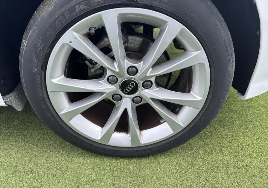 Gros plan sur la jante alliage 5 branches parallèles de couleur argentée d'une Audi A3 Sportback blanche.