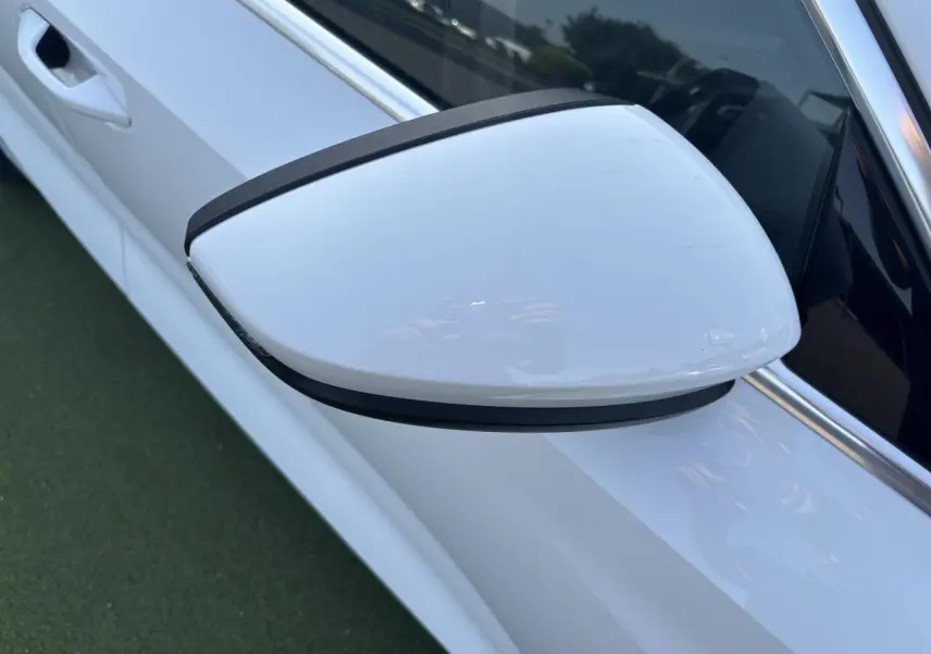 Rétroviseur côté gauche blanc Arkona de l'Audi A3 Sportback 2024, avec poignée de porte visible en arrière-plan.