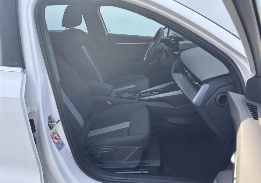 Intérieur avant droit d'une Audi A3 Sportback 2024 blanc Arkona avec sièges tissu noir et console centrale moderne.