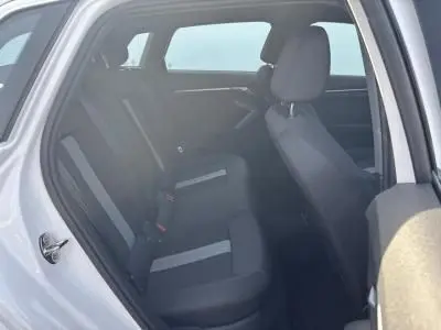 Vue intérieure côté gauche arrière de l'Audi A3 Sportback 2024 blanc Arkona, montrant les sièges tissu noir avec accoudoir central.