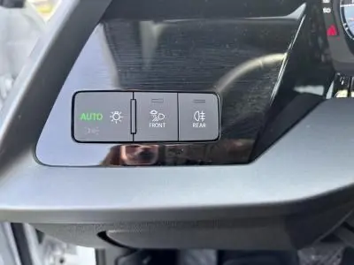 Gros plan sur les commandes d'éclairage à gauche du volant d'une Audi A3 Sportback blanche de 2024.