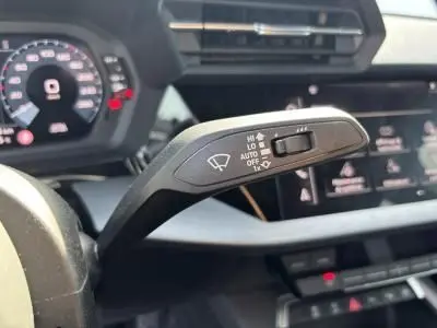 Gros plan sur la commande des essuie-glaces à l'intérieur de l'Audi A3 Sportback blanc Arkona, tableau de bord en arrière-plan flou.