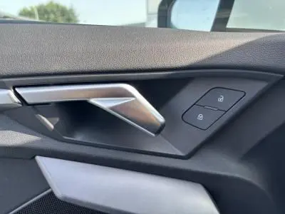 Poignée de porte intérieure côté gauche de l'Audi A3 Sportback blanc Arkona, avec commandes de verrouillage intégrées.