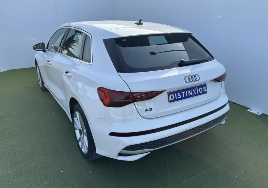 Audi A3 Sportback blanc Arkona vue 3/4 arrière droit, avec feux arrière LED et jantes alliage 5 branches parallèles.